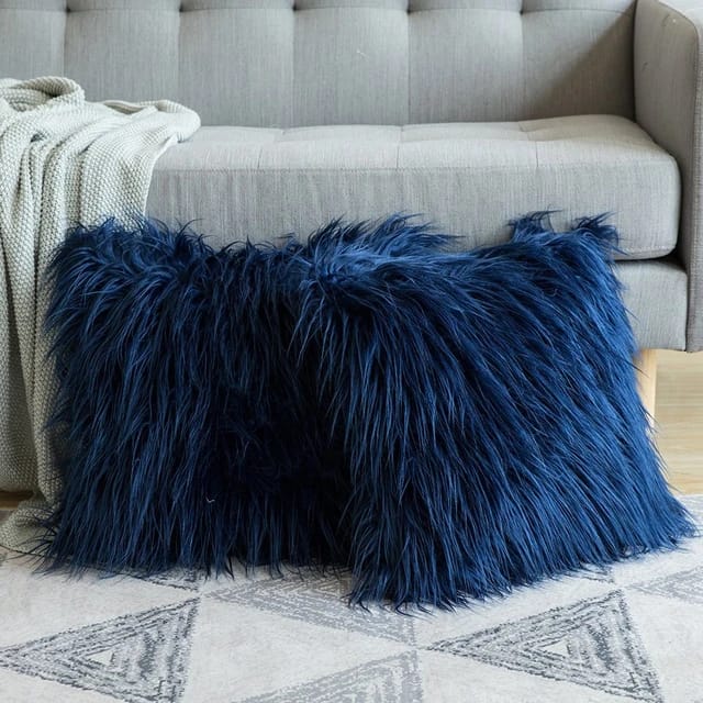 Cojines decorativos de peluche azul oscuro sobre un sofá