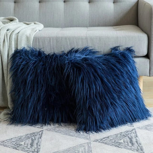 Cojines decorativos de peluche azul oscuro sobre un sofá